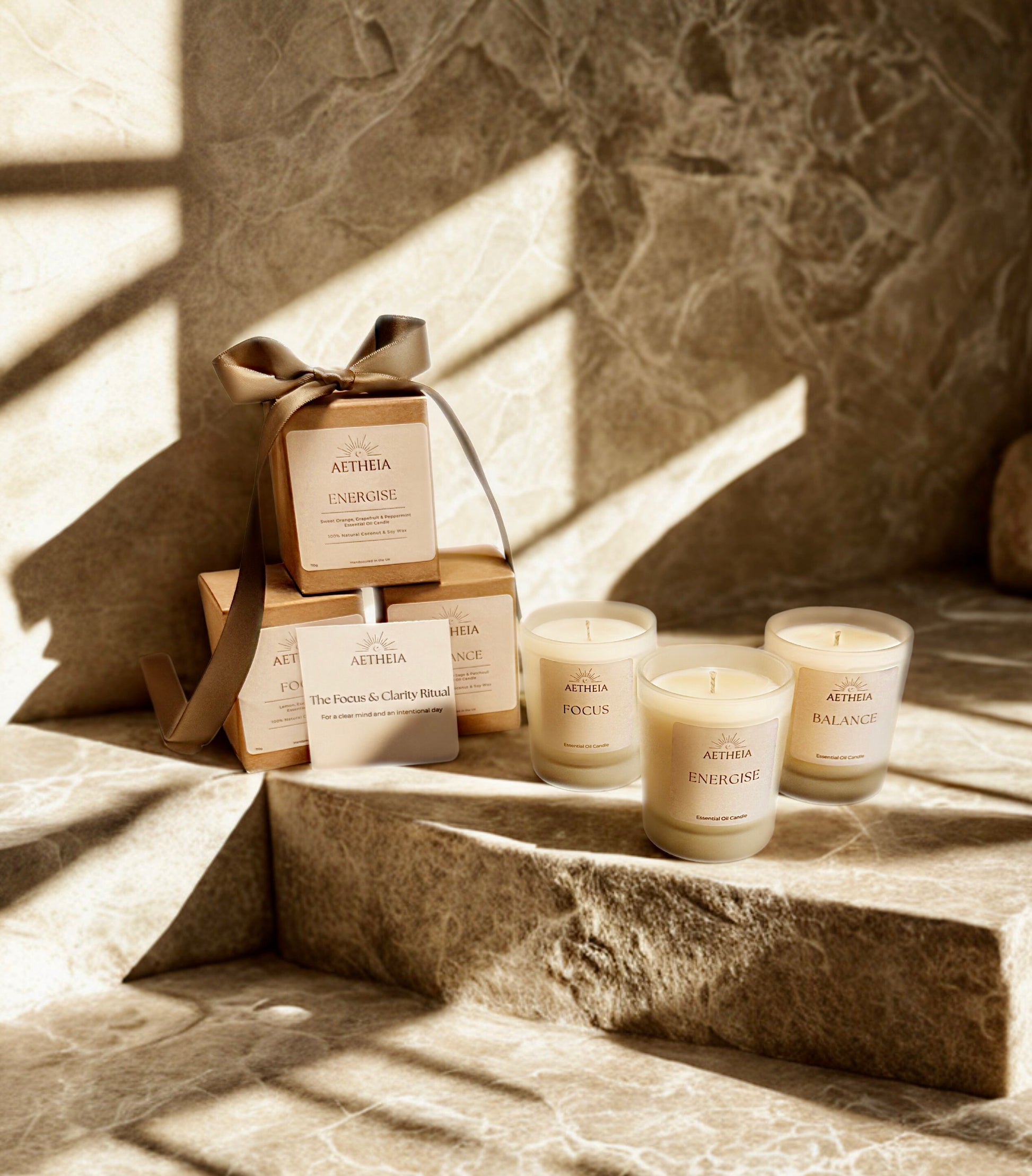 Aetheia discovery set candles and boxes on a stone surface with sunlight casting shadows.